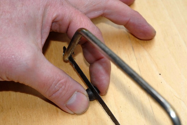 Lotus seed being held between fingers and sawn with a hacksaw